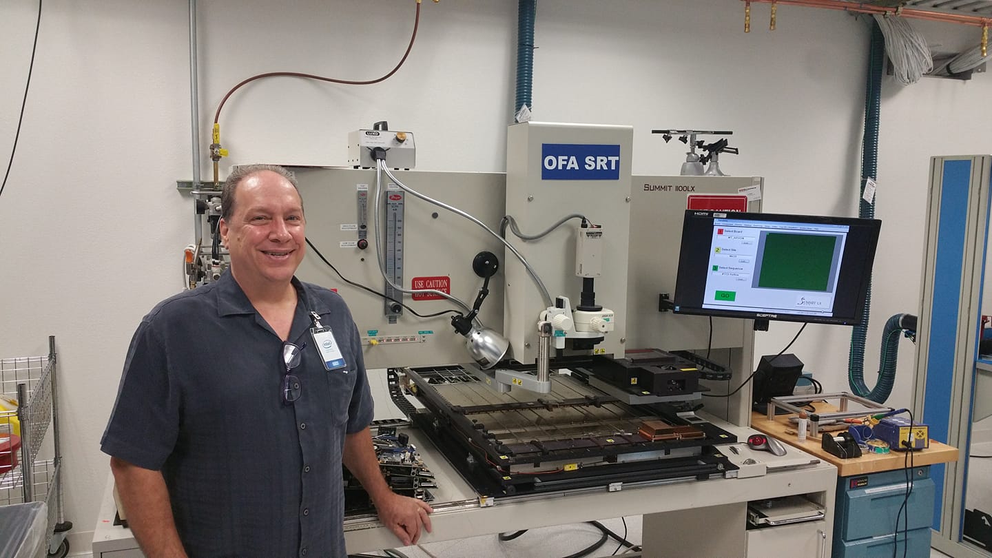 A man standing next to a fully automatic gray BGA rework station with a monitor