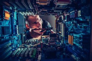 Man repairing circuit boards with long-handled pliers